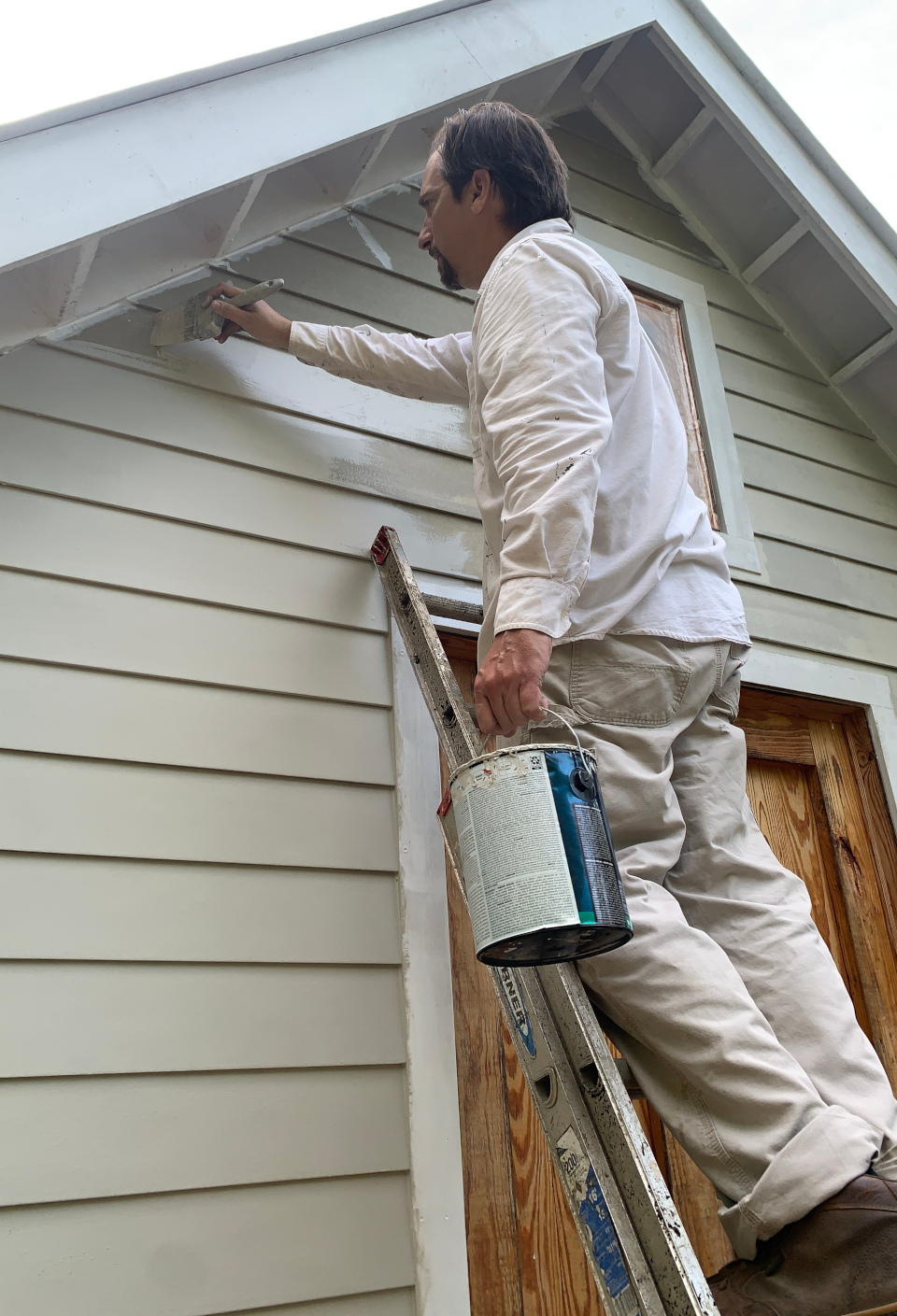 Painter brushing fresh paint onto exterior siding on a home in Gordonsville VA