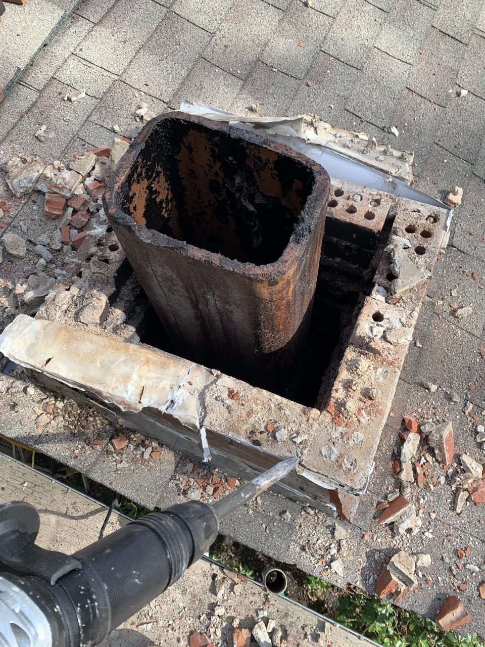 The top bricks are removed using a hammer drill, breaking down the chimney safely.