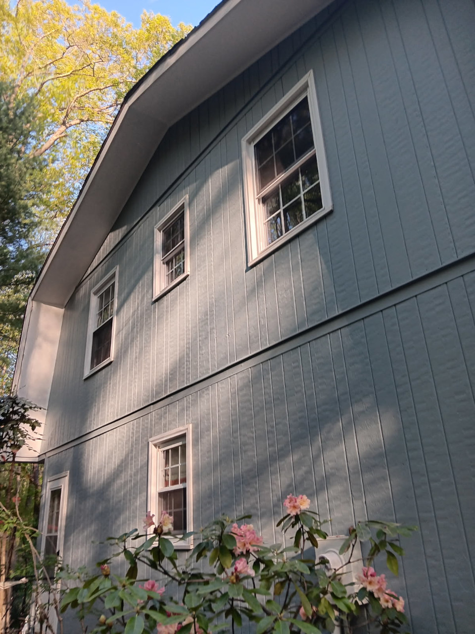 The repaired soffit and siding are completed and painted, shown from the ground.