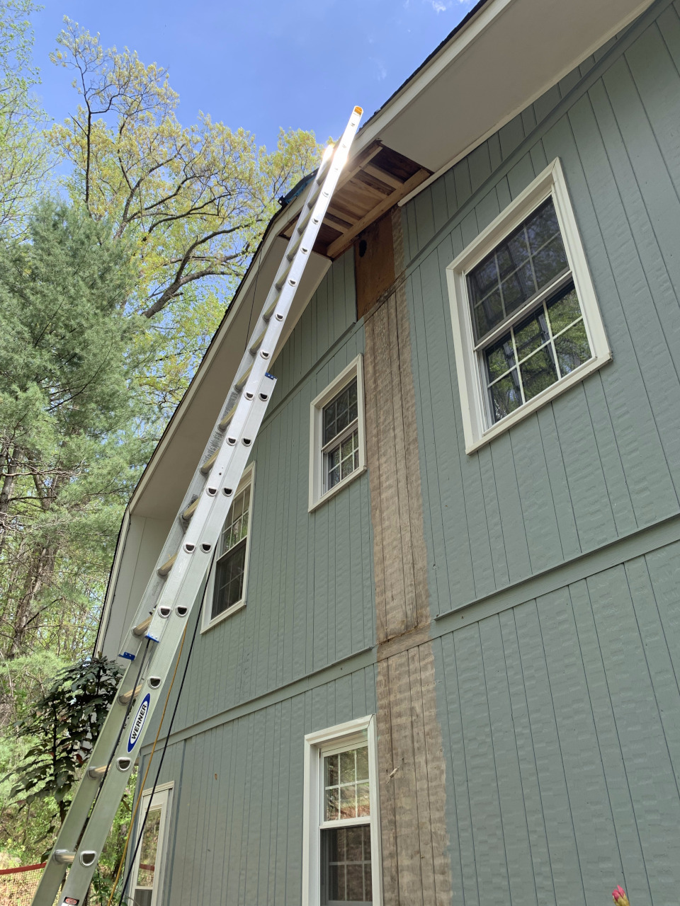 From ground level, the new framing is visible stabilizing the rotted sections within the soffit.