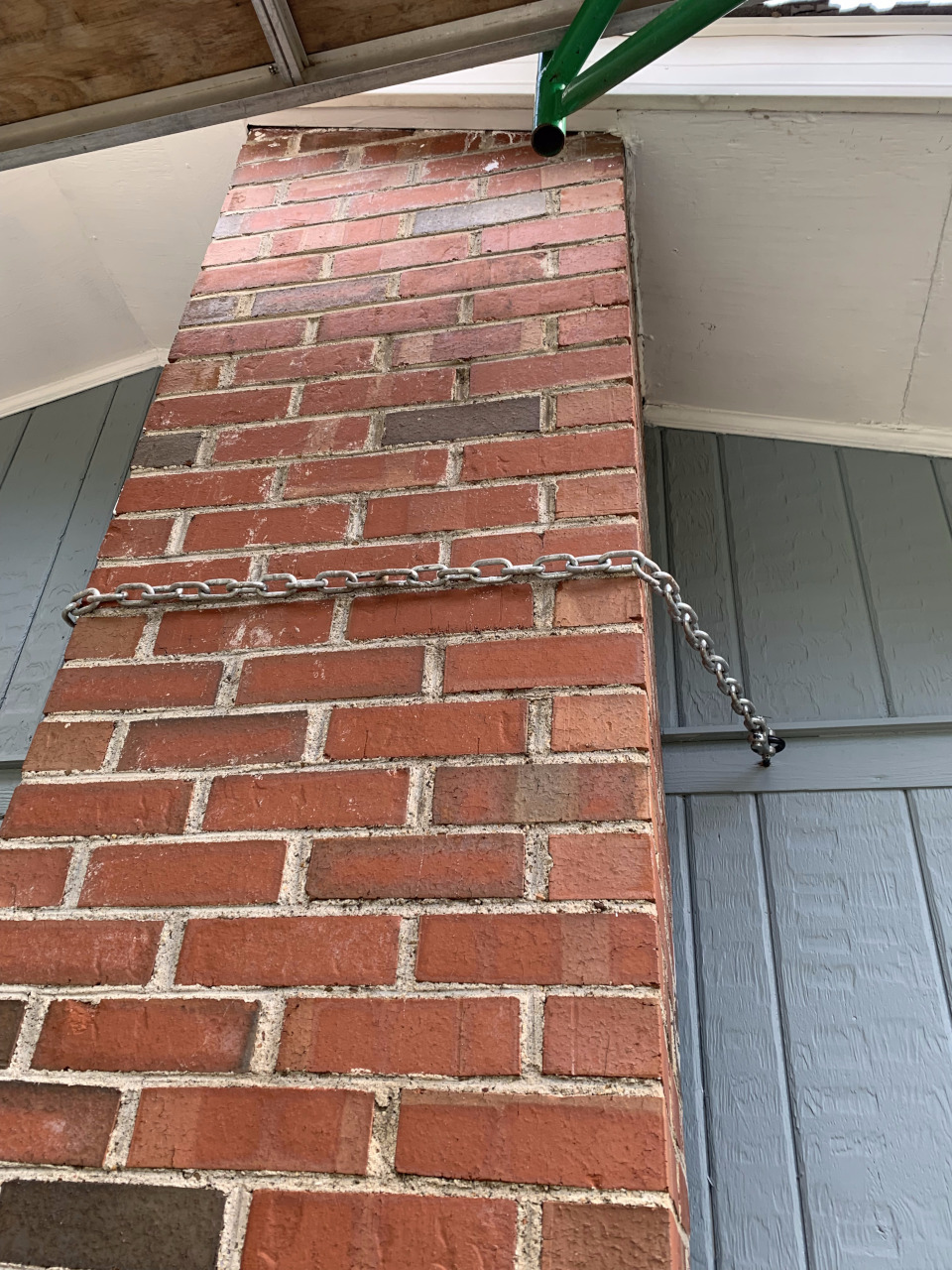 Chains and eyebolts secure the chimney to the house for temporary stabilization.