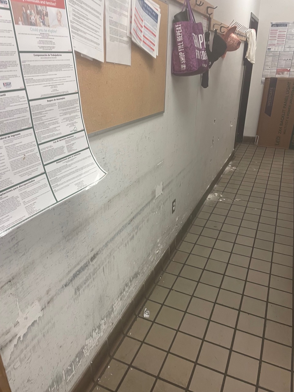 Badly deteriorated sheetrock wall with missing chunks, black smudges, discolorations, and scrapes.