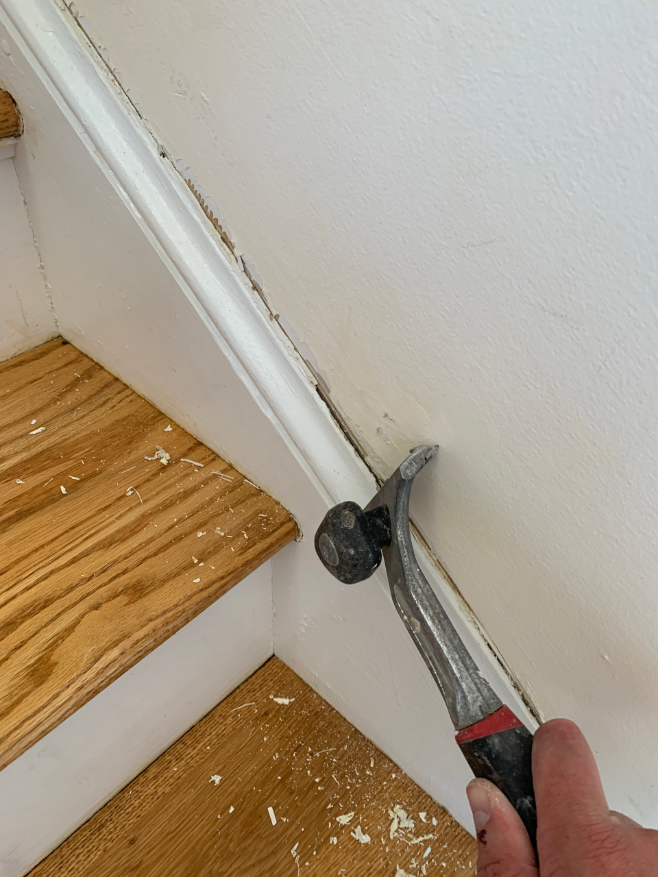 Removing the cracked caulk line along the sheetrock joint to correct the underlying defect.