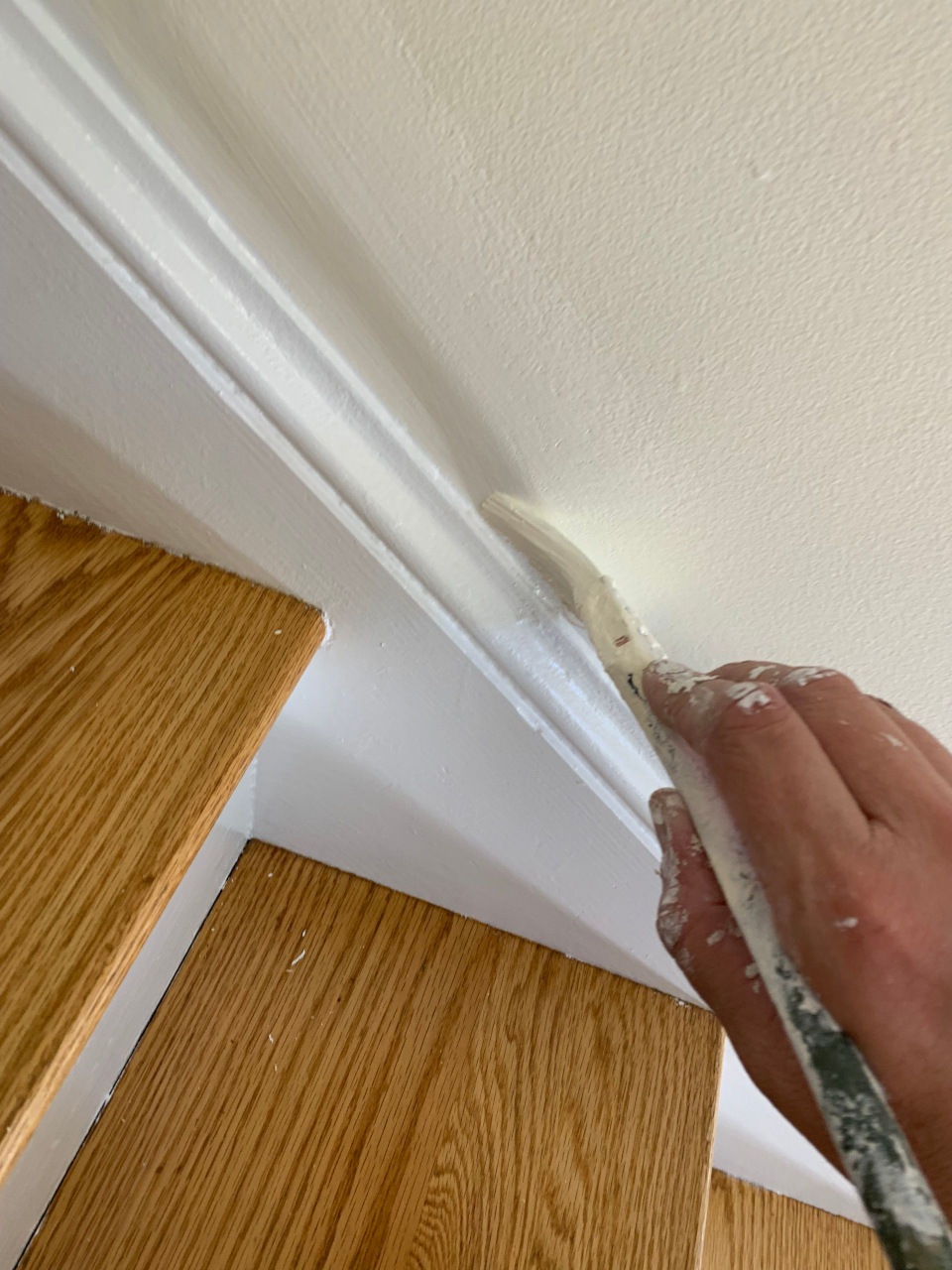 Cutting in along the repaired sheetrock joint to establish crisp, clean borders.