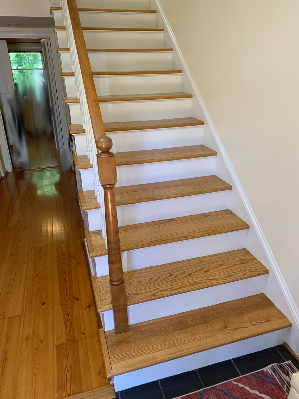 Completed stairway with restored trim and freshly painted walls, view one.