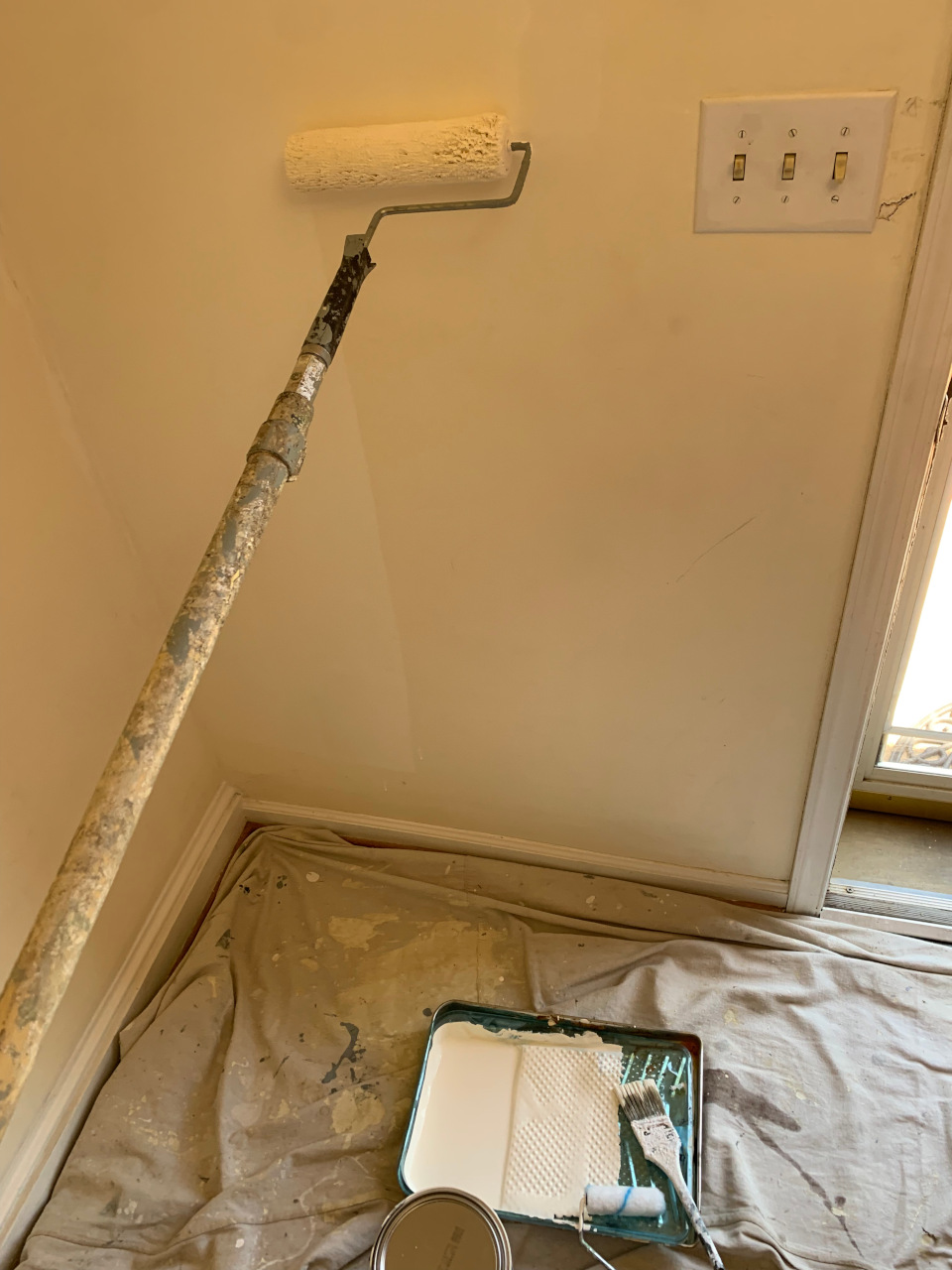 Rolling fresh paint onto the wall, transforming the stairway surface.