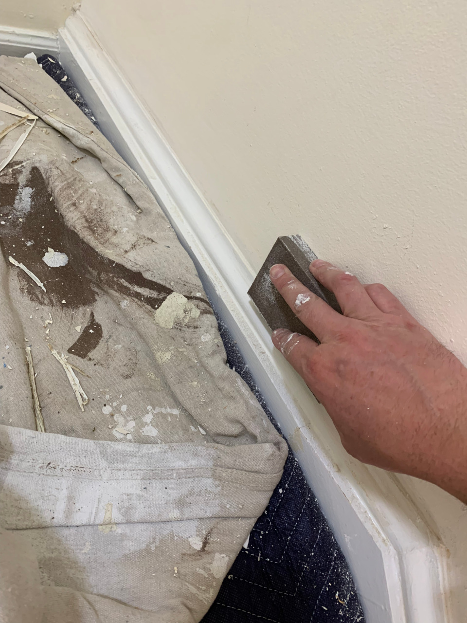 Sanding the cured putty to refine the trim and prepare it for a fine-finish coat.