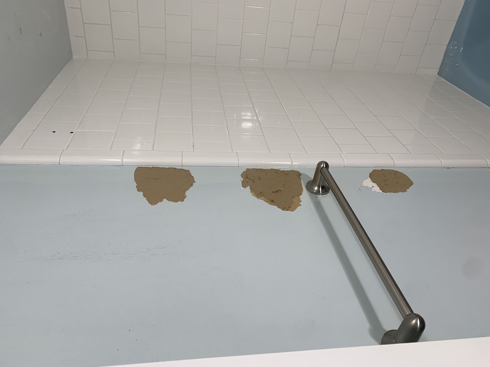 Before: Three spots on the bathroom wall where the paper facing had torn away, leaving bare brown paper exposed.